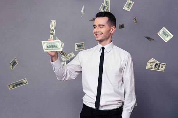 istock Smiling businessman standing under rain with dollar money 502291404