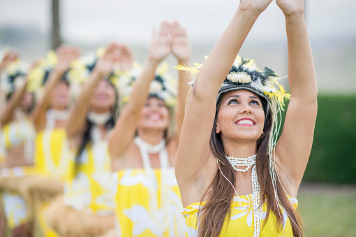 A group of women are doing a traditional Hawaiian dance during a luau for tourists on vacation.