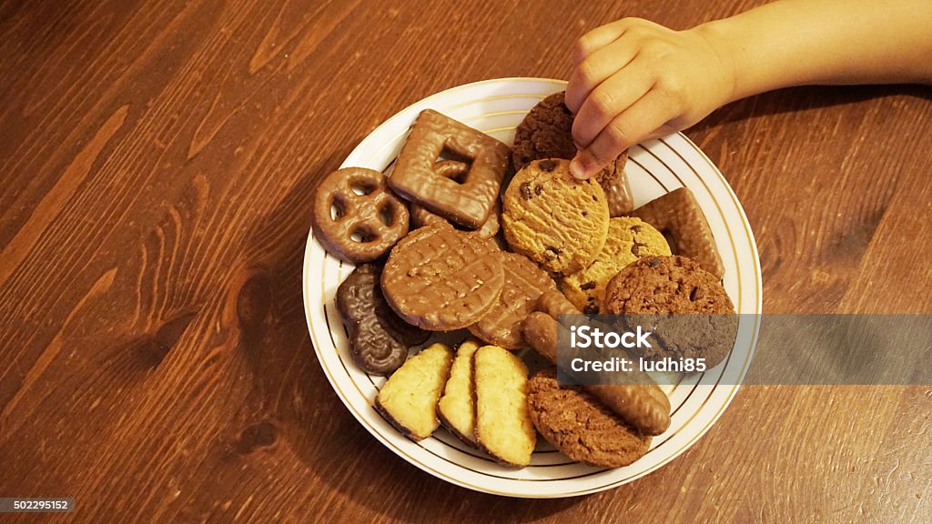 Hand grabbing biscuits from a plate Plate of assorted biscuits Gripping Stock Photo