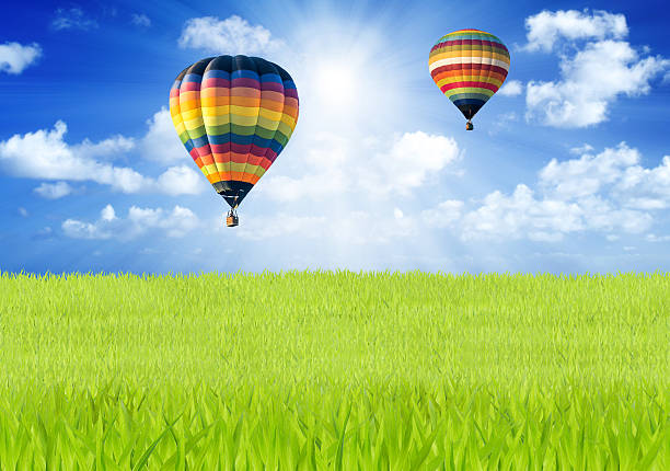 Hot air balloon over green fields and blue sky background