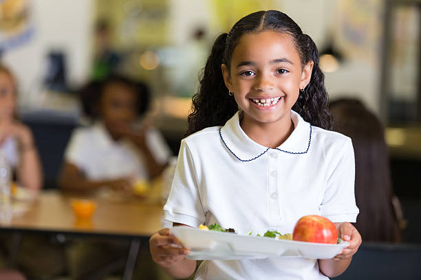 cute little girl in school cafeteria with food tray - schoollunch stockfoto's en -beelden