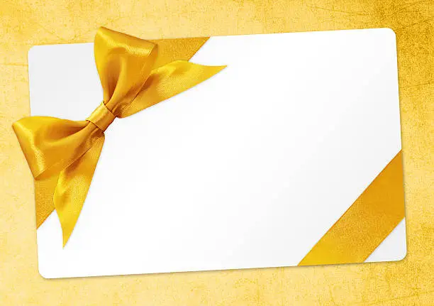 Photo of gift card with golden ribbon bow Isolated on yellow background