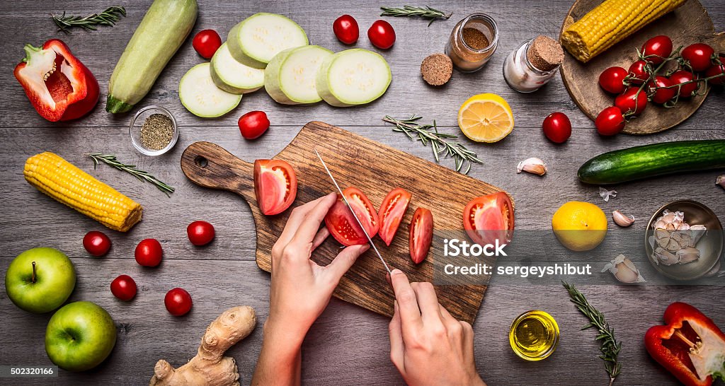 Feminino mão corte de tomate rústico kitchen table, vegetariana conceito. - Foto de stock de Legume royalty-free