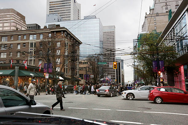 Vancouver, Canada - December 19, 2015: Intersection at Burrard and Robson, Downtown Vancouver, Canada. Pedestrians and traffic flow through the busy central business district on an autumn afternoon.