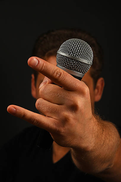 istock Hand with microphone and devil horns isolated on black 502324550