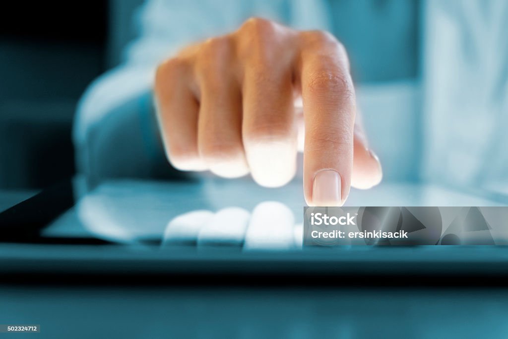Woman using digital tablet Woman hand touching screen digital tablet pc. Closeup shot. Small depth of field. Soft focus. Blue Stock Photo