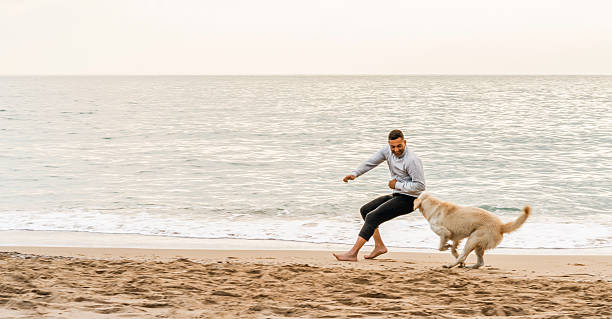 istock Man and his dog running a beach 502329362