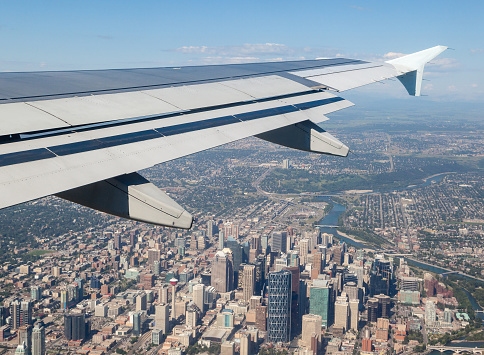 Airplane window view showing wing of the plane flying over downtown Calgary on liftoff.