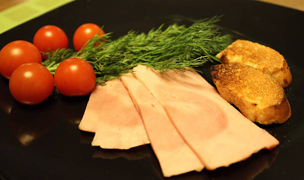 istock Sliced ham, cherry tomatoes and greens closeup 502349940