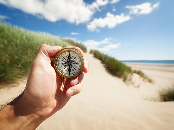 mano agarrando una brújula - compass exploration the way forward beach fotografías e imágenes de stock