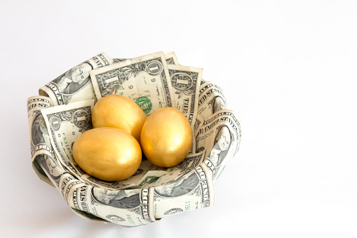 Image of three golden eggs sitting in a nest made of dollar bills.  The nest is set against a white background.   The eggs represent three separate investments, or nest eggs, of equal size.