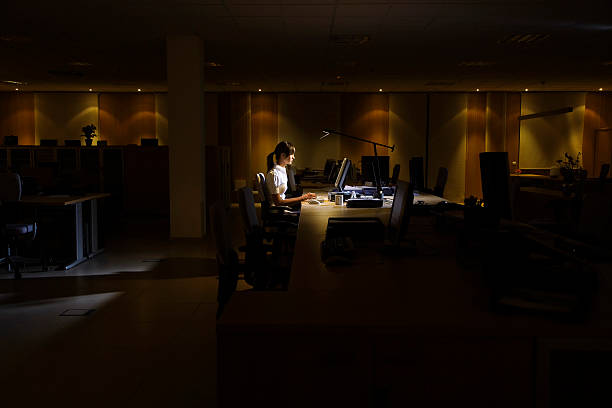 Woman Using Computer In Dark Office stock photo