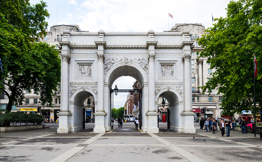 London, United Kingdom - August 7, 2011: People are seen walking near Marble Arch, which was designed in 1828 by John Nash and modeled after the Arch of Constantine in Rome. The arch was originally erected near Buckingham Palace, but was moved to its present location on the northern side of Hyde Park in 1855.
