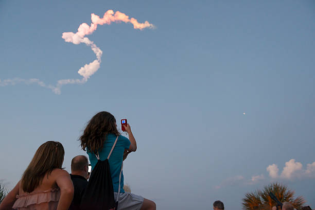Rocket launch at Cape Canaveral Port Canaveral, Florida, USA - May 24, 2013: Spectators at Jetty Park in Port Canaveral use their smart phones to photograph a Delta IV launch in the evening sky. The rocket launched from Space Launch Complex 37B at Cape Canaveral Air Force Station and carried a $342 million U.S. military communications satellite, the Wideband Global SATCOM (WGS-5). cocoa beach photos stock pictures, royalty-free photos & images