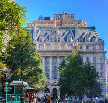 New York, NY, USA - July 6, 2014: The Surrogate's Courthouse, also known as the Hall of Records, is a municipal building in lower Manhattan. The building was designed by John R. Thomas and built between 1899 and 1907.  The building is on the National Register of Historic Places since 1972. It was designated a National Historic Landmark in 1977. Currently it houses the city's Municipal Archives, as well as the Surrogate's Court for New York County. 5 black street performers are getting ready for the street show. People are walking around. HDR image of backlit scene.