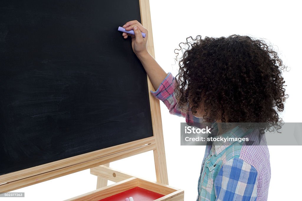 Young school child writing on blackboard Little girl writing on classroom chalkboard Beautiful People Stock Photo