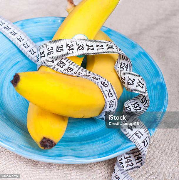 Bananas With A Tape Measure Wrapped Around It Stock Photo - Download Image Now - Backgrounds, Banana, Blue