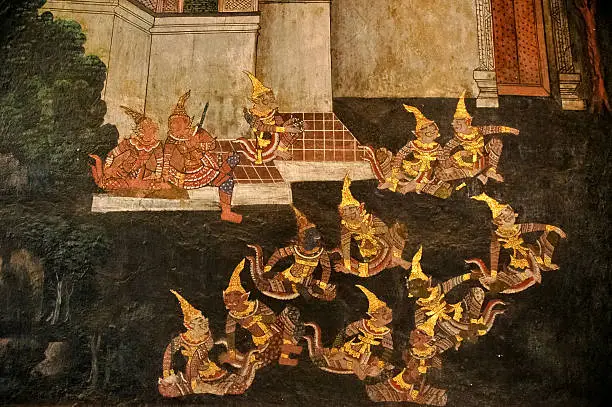 Golden Thai Ramayana drawing on a wall. This ancient drawing is a public domain in a wall of old grand temple in Bangkok, Thailand. The photo displays giants royal army planning to attack human tribe.