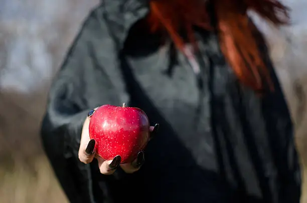 Witch from fairy tale about Snow White offers to eat an poisoned apple. Selective focus.