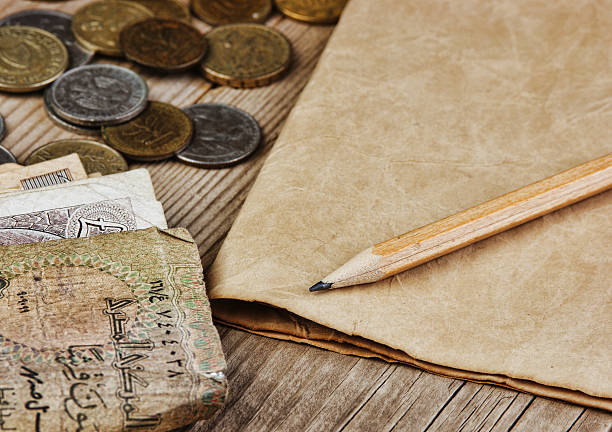 istock Old notes and coins and pencil on a wooden table 502379389