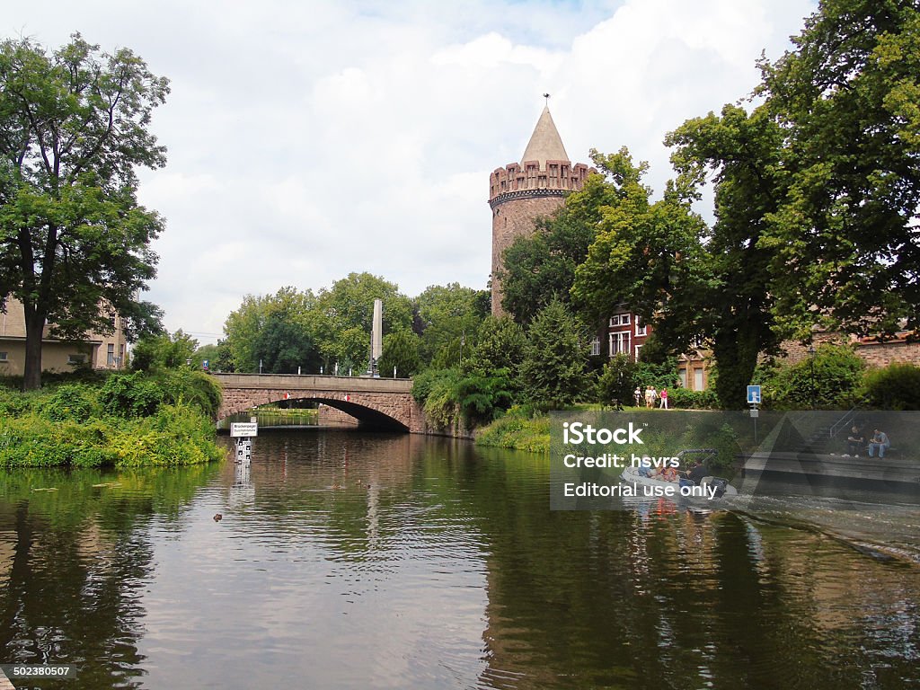 Brick town wall tower Brandenburg an der Havel, Germany - July 16, 2014: A smart boat drives along on the Havel River at the Historic town of Brandenburg an der Havel towards to a lock. On right side the brick tower (Steintorturm) of the old city wall. some people sitting on bench eating. Activity Stock Photo