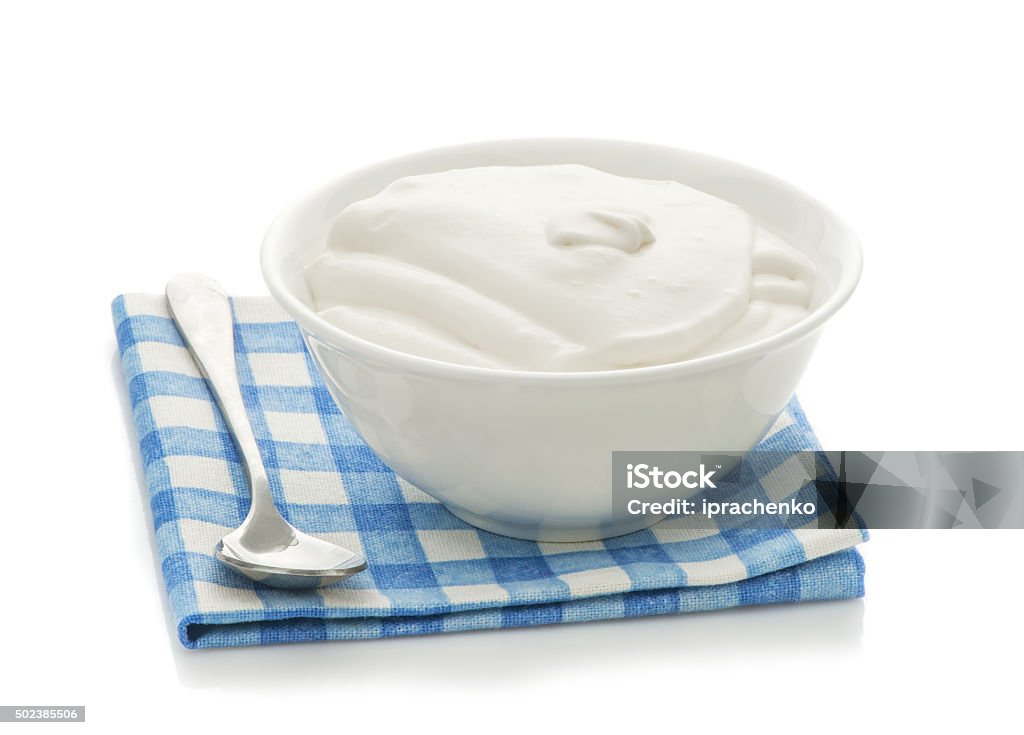 Rural natural sour cream in bowl Rural natural sour cream in bowl, a spoon and a checkered napkin isolated on a white background 2015 Stock Photo