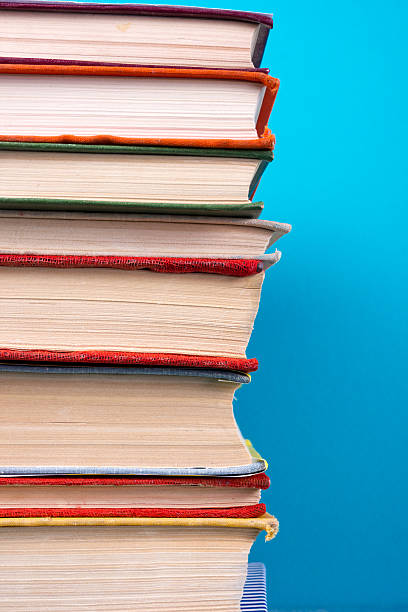 istock Stack of colorful hardback books, open book on blue background 502393112