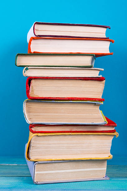 istock Stack of colorful hardback books, open book on blue background 502393228