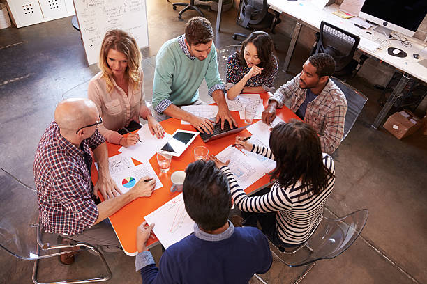 istock Overhead View Of Designers Having Meeting Around Table 502394656