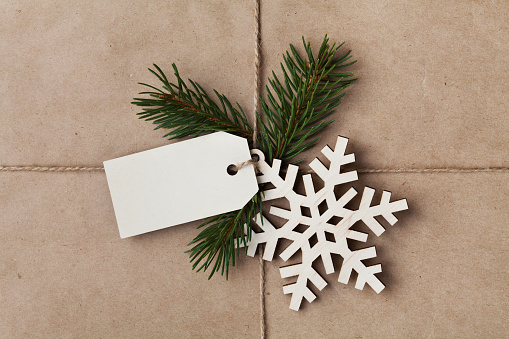 String or twine tied in a bow with tag, fir tree and wooden snowflake on kraft paper texture