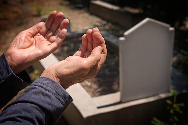 muslim woman hands praying near the grave stock photo
