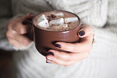 Brown cup with cocoa and marshmallow in the hands