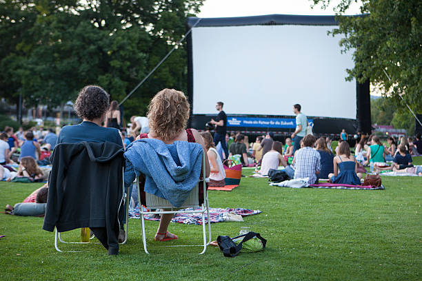 Spectators at Open-Air cinema Wiesbaden, Germany - July 18, 2014: Spectators of Open-Air Cinema event at Reisinger park in the city center of Wiesbaden, Germany - sitting on the grass and folding chairs, waiting for the beginning of the movie photography hessen germany central europe stock pictures, royalty-free photos & images