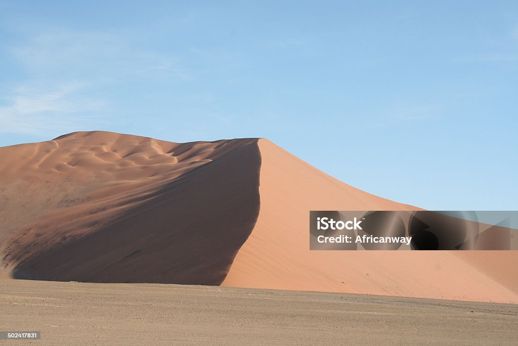 Dunes of Sossusvlei, Namib Desert, Namibia, Africa The desert sand dunes in Sossusvlei, Namibia are part of a beautiful Namib Desert landscape in Africa.Their orange color comes from a high percentage of iron in the sand and oxidation processes. The name Sossusvlei comes from "vlei", which is the Afrikaans word for "shallow minor lake" and "sossus" is the Nama word for "dead end". Big Daddy is the highest dune in the Sossusvlei area with a height of about 325 meters. Adventure Stock Photo