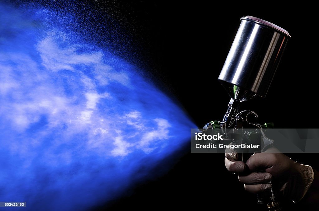 Spray gun in hand on dark background Painter painting with spray gun. Dark background. Auto Repair Shop Stock Photo