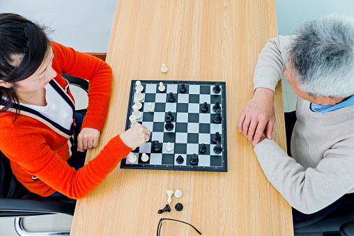 Senior man playing chess with his daughter.