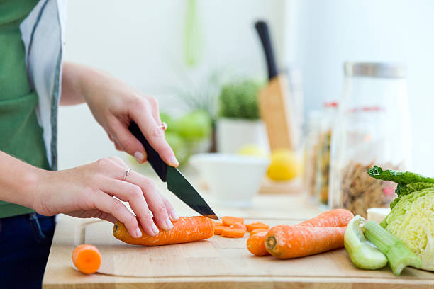 istock Pretty young woman cutting vegetables in the kitchen. 502447266