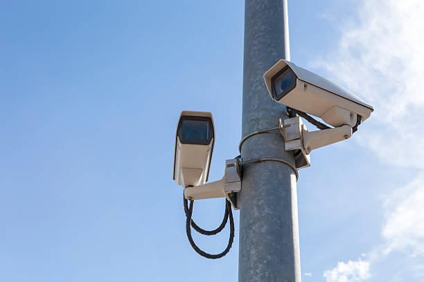istock two cctv on metal light pole , blue sky background 502447389