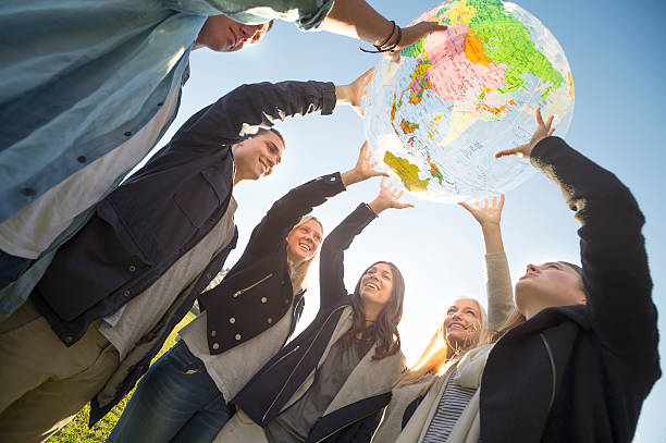 group of people holding a world globe - adolescence teenager globe map fotografías e imágenes de stock