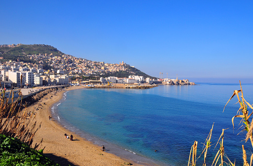 Algiers, Algeria: Rmila / Nelson beach in Bab El Oued, with Notre Dame d'Afrique cathedral and Z'ghara and Bologhine quarters in the background - Algiers bay - golden sand by the Mediterranean sea - photo by M.Torres