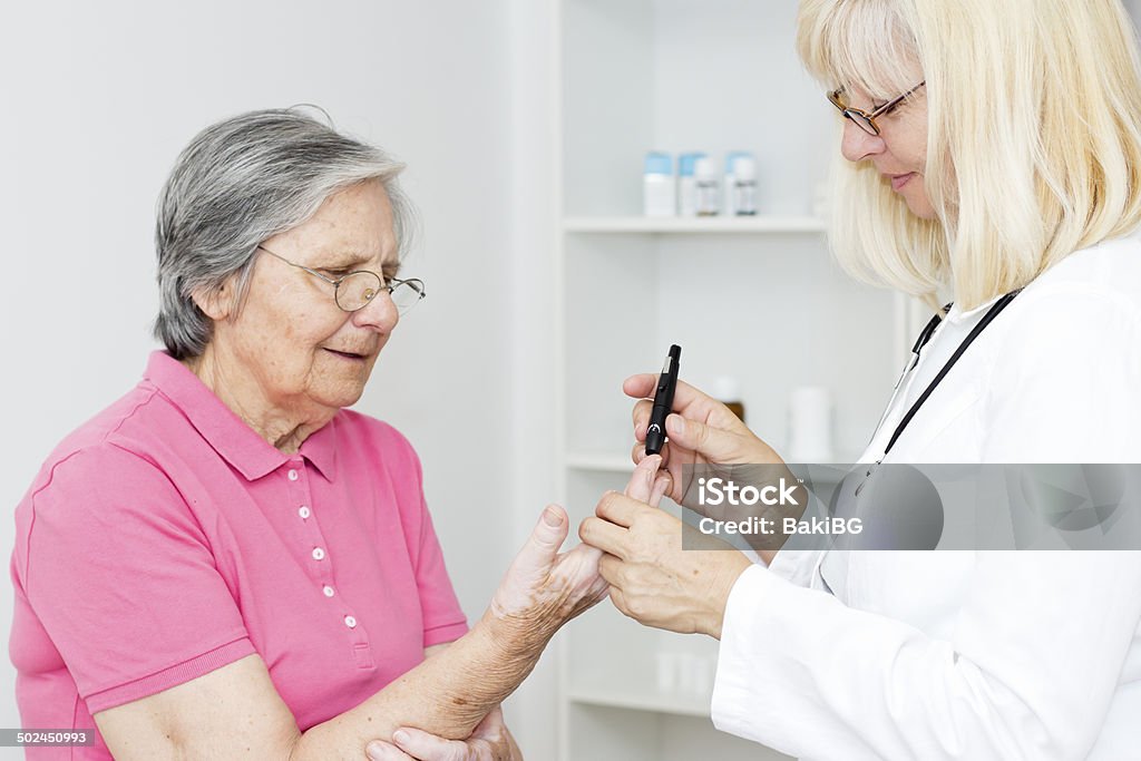 Diabetes test Female doctor Checking Blood Sugar Level to senior patient. Glucometer Stock Photo