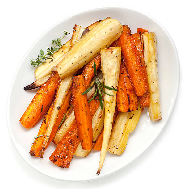 Roasted Parsnips and Carrots Overhead View Roasted parsnips and carrots garnished with rosemary and thyme.  White plate, overhead view. roasted stock pictures, royalty-free photos & images