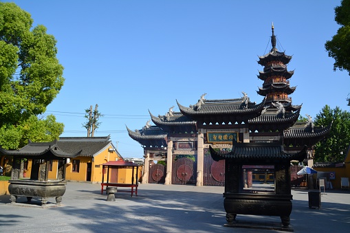 Shanghai, China - May 22, 2014: The old Longhua Temple, a Buddhist Temple dedicated to the Maitreya Buddha. In the background the Longhua Pagoda, on a clear sunny day. It is the largest, most authentic and ancient temple complex in Shanghai.