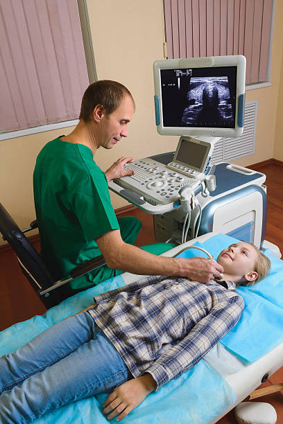 girl getting ultrasound of a thyroid from doctor stock photo