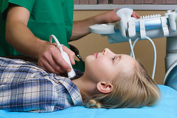 girl getting ultrasound of a thyroid from doctor stock photo
