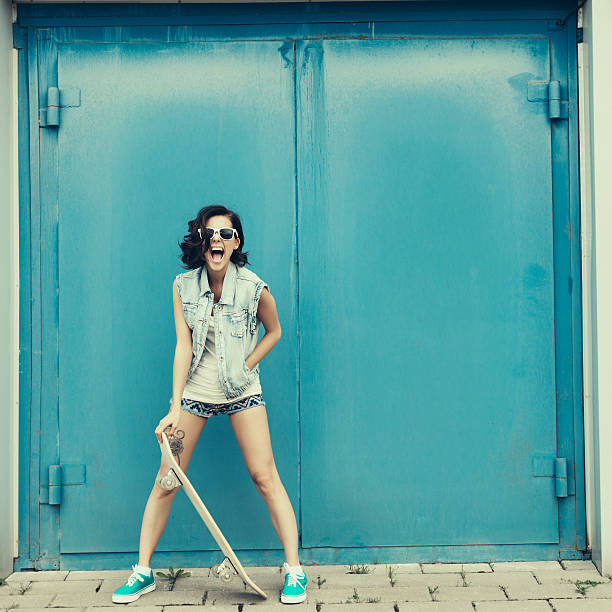 young brunette frau posieren mit skateboard - city life funky cool urban scene stock-fotos und bilder