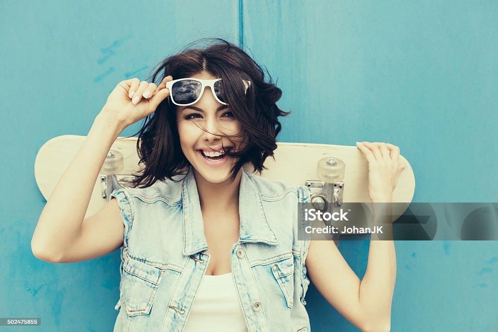 Young brunette woman posing with skateboard Young girl in sunglasses posing with skateboard. Lifestyle outdoor toned portrait Teenager Stock Photo