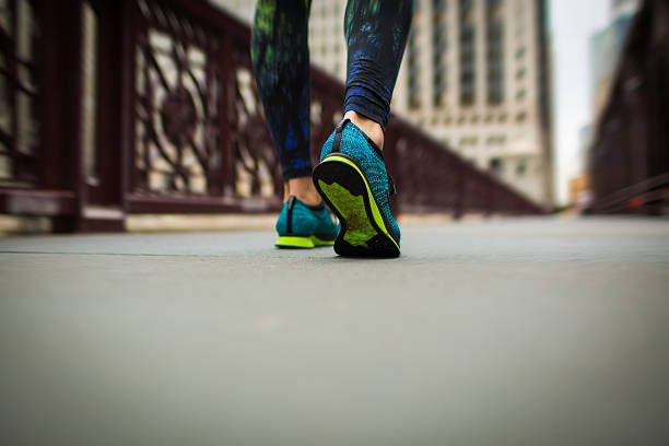 Runner feet running on road closeup on shoe. woman fitness sunrise jog workout wellness concept. 