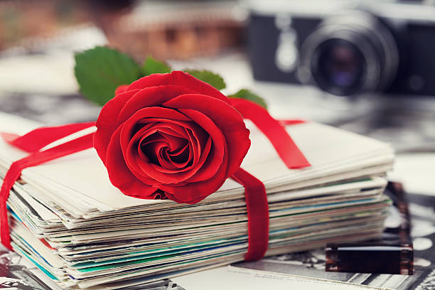 Stack of postcard and photograph tied with velvet ribbon and red rose, film and vintage camera