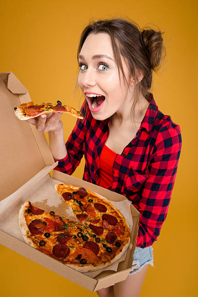 istock Joyful charming young woman standing and tasting pizza 502497162